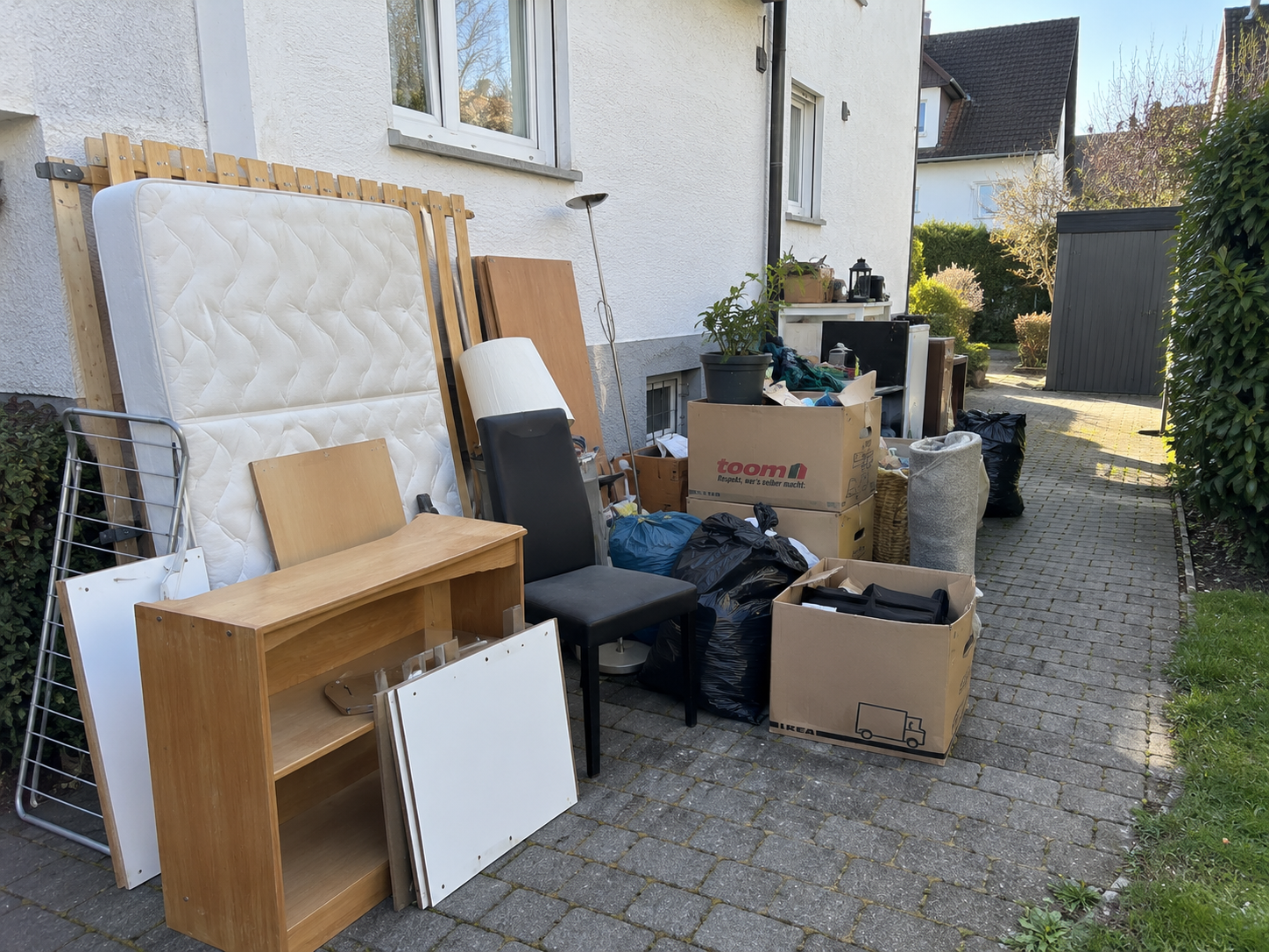 Zur Entrümpelung bereitgestellte Möbel, Säcke und Hausrat vor einem Wohnhaus.