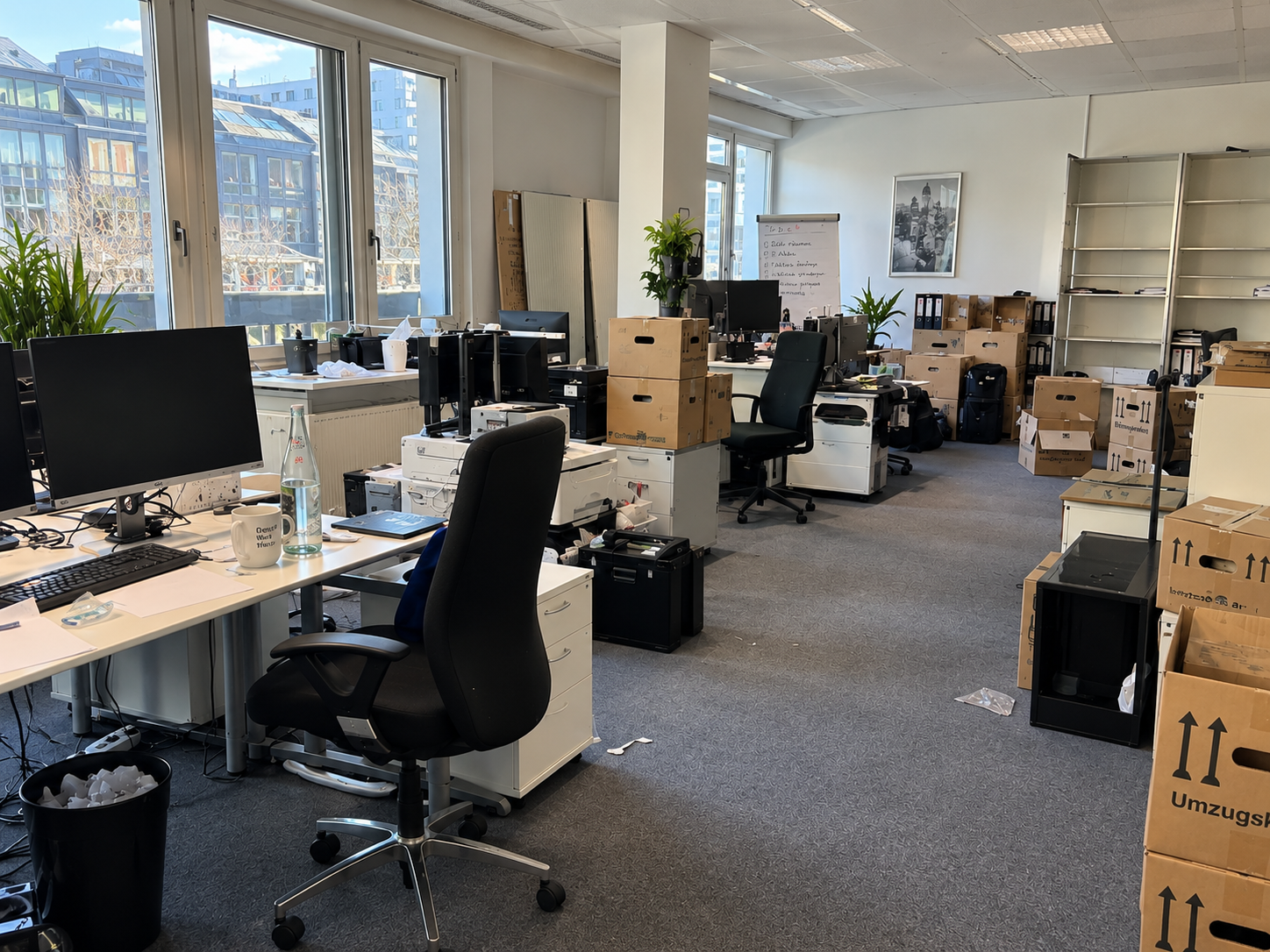 Büro mit Arbeitsplätzen, Kartons und Mobiliar vor einer Firmenauflösung.