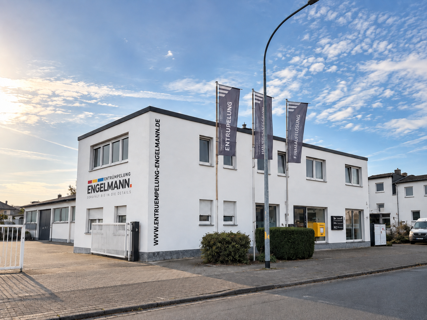 Das Firmengebäude von Entrümpelung Engelmann mit Fassadenlogo und Fahnen.